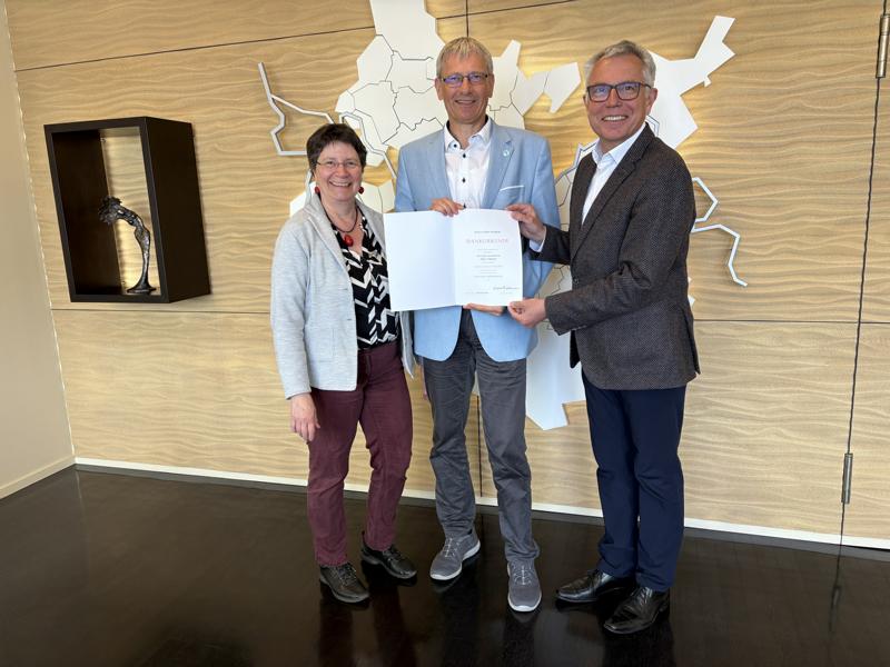 Stefan Hildebrandt (Mitte) 40 Jahre im Öffentlichen Dienst: Landrat Stefan Dallinger (rechts) gratuliert seinem Stellvertreter herzlich zum Dienstjubiläum. Mit dabei ist Nicole Gross (links), Ehefrau des Ersten Landesbeamten